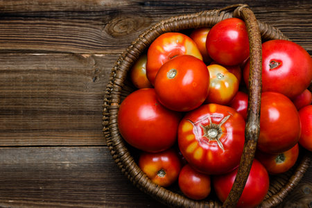 Basket of fresh tomatoes on wooden table, top view.の写真素材