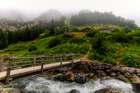 Highland houses and wooden bridge in foggy weather