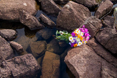 Water among basalt rock fragments and a bunch of colorful flowers in Turkeyの写真素材