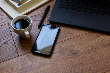 standing on wooden floor, next to computer, phone and notebook-pen