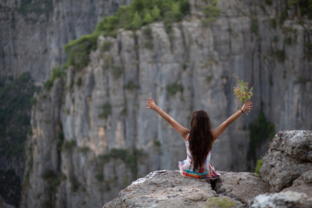 The young girl with flowers in her hand, who made a sign of victory while watching the canyon view.