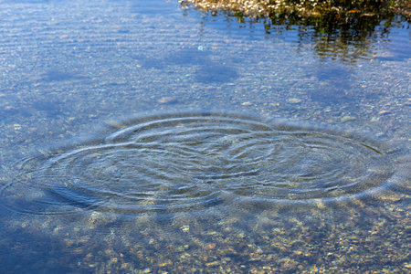 Round droplets of water over circles on the pool water. Water drop, whirl and splash. Ripples on sea texture pattern background. Desktop / laptop wallpaper. Closeup water rings affの写真素材