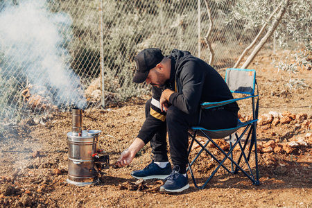 Man lighting samovar for tea, coffee, hot water in camp.