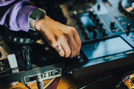 DJ plays live set and mixing music on turntable console on stage at nightclub. Disc Jockey Hands on a sound mixer station at club party. DJ mixer control panel for playing music and partying.の写真素材