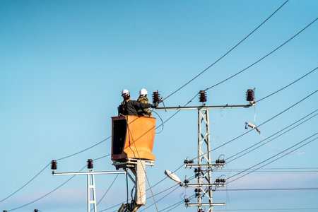 Electrical workers are making a high voltage connection. Electricity poles and cables.の写真素材