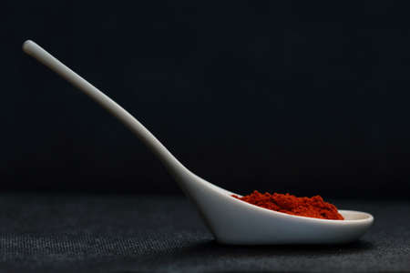 White spoon with paprika on black backgroundの写真素材