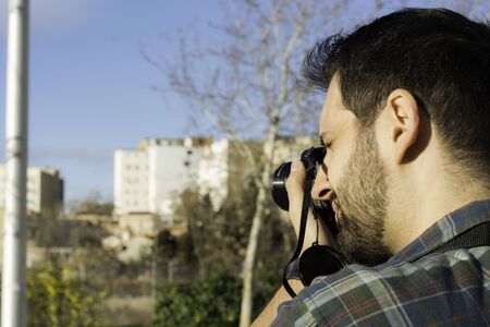 Handsome hipster using camera at the street