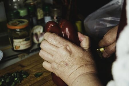 Woman in her kitchen slicing pepperの写真素材