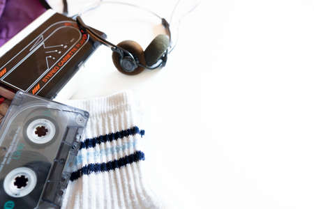 Medium short shot, white background representing elements of the 1990s. Basic 90's kit, purple backpack, cassette tape player, retro headphones, cassettes and high socks with blue stripes.の写真素材