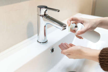 Medium close-up, woman using soap to wash her hands in the bathroom at home. Close-up of the concept of hand hygiene. Protection against infections and viruses.の写真素材