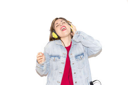 Portrait of modern young girl singing, while listening to music isolated on white background, wearing colorful casual clothes and accessories. People's lifestyle concept.の写真素材
