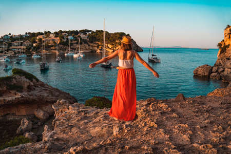 Young woman on holiday with her arms stretched out happily looking at the landscape, in the cove of Portal Vells, island of Palma de Mallorca, Spain.の写真素材