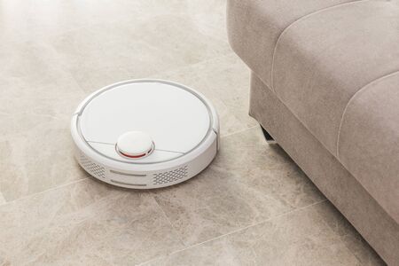 Stock photo of a robot vacuum cleaner cleaning the roomの写真素材