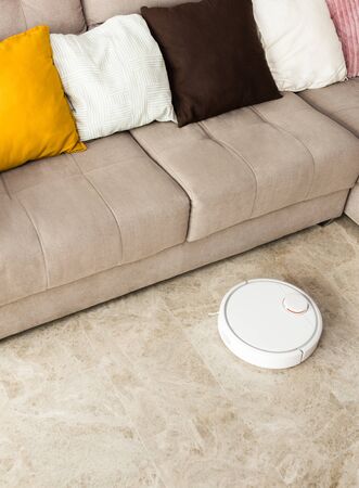 Stock photo of a robot vacuum cleaner cleaning the roomの写真素材