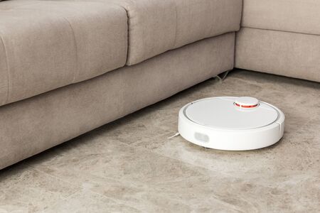 Stock photo of a robot vacuum cleaner cleaning the roomの写真素材