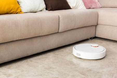 Stock photo of a robot vacuum cleaner cleaning the roomの写真素材