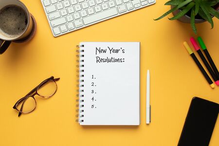 Stock photo of 2020 new year notebook with list of resolutions and objects on yellow backgroundの写真素材