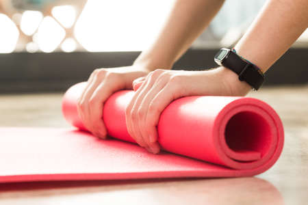 Stock photo of a young woman rolling the mat after exercising at home in the living roomの写真素材