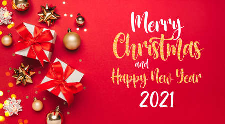 Merry Christmas and Happy New Year 2021 greeting card background with lettering. Christmas gifts and golden decor on red background top view. Winter xmas holiday theme in flat lay styleの写真素材