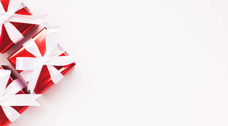 Merry Christmas and Happy Holidays greeting card background with copyspace on the right. Three Christmas gifts on white background top view. Winter xmas holiday theme in flat lay styleの写真素材