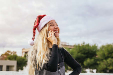 Stock photo of a young blonde girl having a Christmas mobile phone call laughing and having fun....