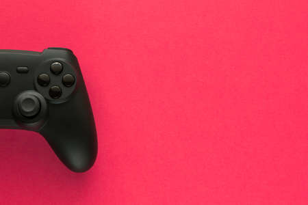Stock photo of a black gamepad on a fuchsia background and copy space on the right side