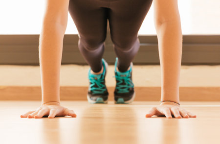 Stock photo of a young woman doing push-ups at homeの写真素材