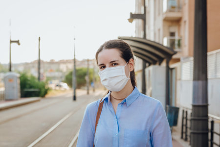 Stock photo of a young woman wearing a face mask at a station waiting for the tram. New normal conceptの写真素材