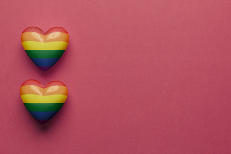 Stock photo of two LGBT plastic hearts on a red background. Hearts on the left side with space for textの写真素材