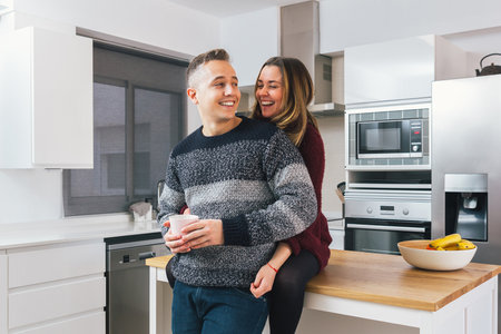 Romantic young couple in love, man and woman hugging and having a great time together in the kitchen at home. Couple life conceptの写真素材