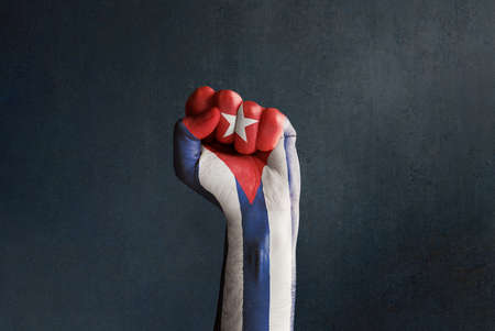 Stock photo of a raised fist with Cuban flag on a dark background and copy space. SOS Cuba, Free Cuba, protests in Cuba against the government fighting for freedom and democracyの写真素材