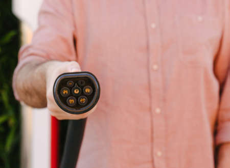 Stock photo of a man holding an electric car or EV socket charger and copy space. Sustainable mobility and Eco-friendly alternative energy conceptの写真素材
