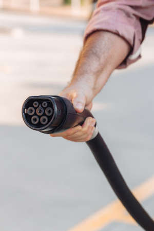 Electric vehicle or EV car socket held by a hand in a charging station. Electrical power supply and Eco-friendly alternative energy conceptの写真素材