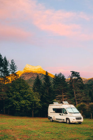 Camper van in a campsite with amazing landscape views of forest and mountains during sunset. Van road trip holiday and outdoor summer adventure. Nomad lifestyle conceptの写真素材