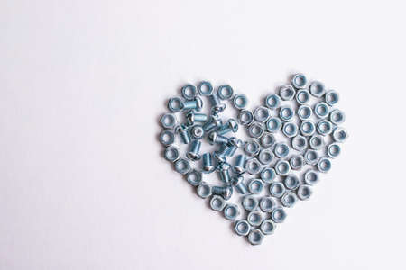 Heart laid out of bolts, nuts on a white background. Fathers Day and wedding anniversary concept.