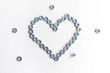 Heart laid out of bolts, nuts on a white background. Fathers Day and wedding anniversary concept.の写真素材