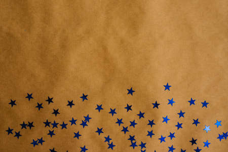 Festive sequins are scattered on the Kraft paper. New year holiday background. Sequins in the shape of blue stars.の写真素材