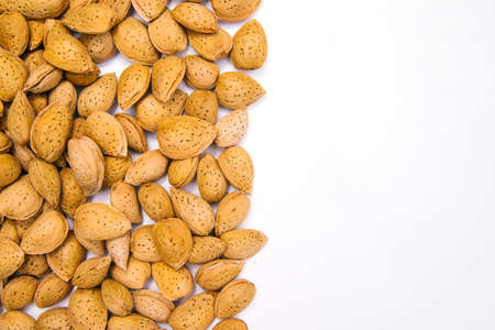 Inshell almonds on a white background. Almonds are arranged in a pile. Almond nut with texture.