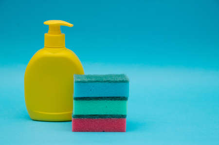 Cleaning products and a sponge for washing dishes on a blue background. Space for text.