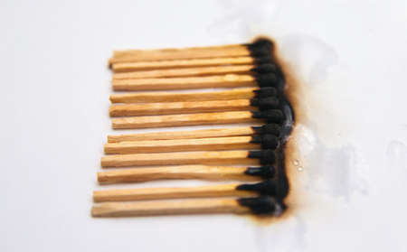 Matches stand in a row on a white background..There are black burnt matches.The fire was...