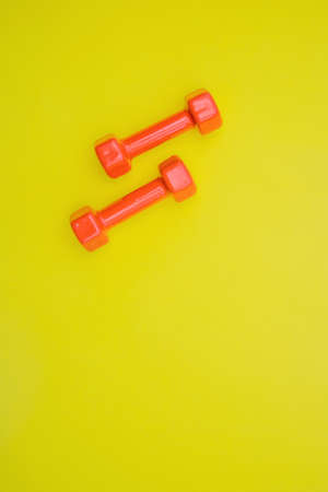 Red dumbbells for sports on a yellow background.の写真素材