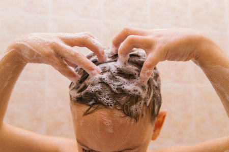 The child washes his head with shampoo. Soap foam on the hair. Hair care.の写真素材