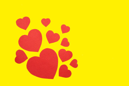 Paper hearts on a yellow background.Valentine's day greeting card.Heart cut out of red cardboard.