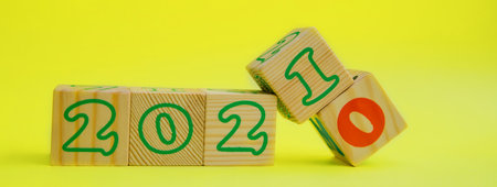 Wooden cubes with the numbers 2021 on a yellow background. The digit 0 is replaced by the digit 1.の写真素材