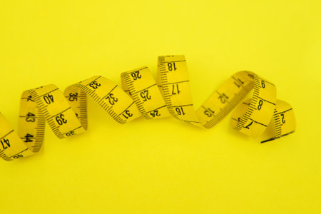Centimeter ribbon of yellow color on a yellow background. A tool for measuring distances. Centimeter for sewing and needlework.の写真素材
