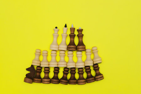 Close-up chess pieces lie in a row on a yellow background. Black and white figures of different designations.の写真素材