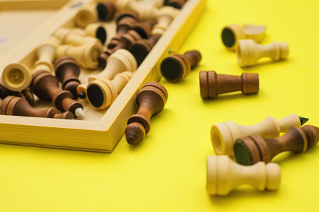 Chess pieces are scattered on a yellow background. Black and white figures of different...