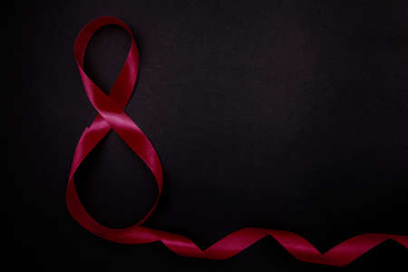 On a black background, a pink satin ribbon in the form of the number eight. Gift wrap. The concept of March 8 and Valentine's Day.A greeting card.の写真素材