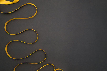 On a gray background, a yellow satin ribbon. The tape lies with bends.Gift wrap.の写真素材
