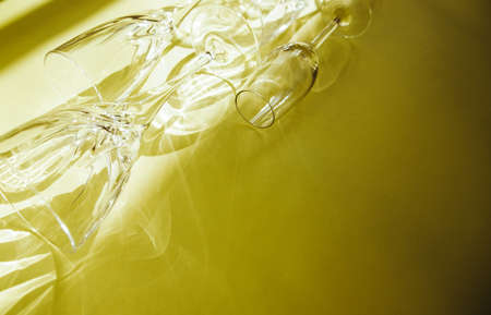 Empty glasses stand on a yellow background, top view. A beautiful creative still life filled with light with hard shadows and highlights from the glass. Sunlight is refracted through the glass.の写真素材